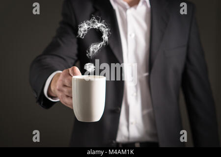 Question mark from coffee steam. Smoke forming a symbol. Business man in a suit holding a hot beverage in a mug and tea cup. Stock Photo
