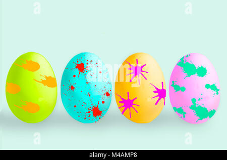 four colorful easter eggs with patches of various colors on pastel colored background Stock Photo