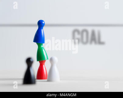 Teamwork, reaching goals, working together and success concept. Colorful board game pawns on each other. Cooperation, leadership and achievement. Stock Photo