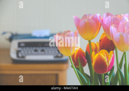 Focus in Foreground Bouquet of Flowers in With a Typewriter in the Background Stock Photo