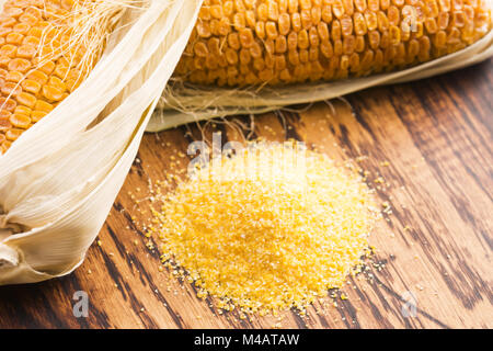 Corn groats and seeds, corncobs on wooden rustic table Stock Photo