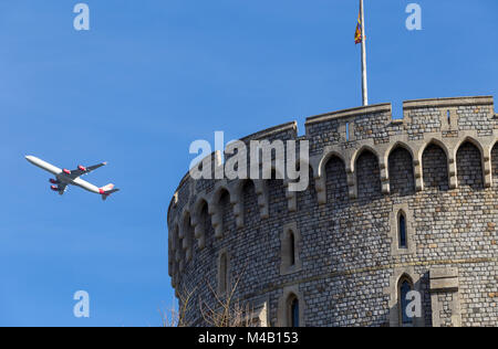 Aircraft / aeroplane / air plane / flight from Heathrow airport over the round tower of Windsor Castle, climbing after take off, & Royal Standard flag Stock Photo