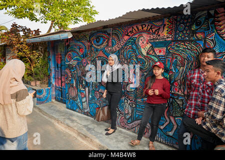 Young people photograph themselves at a colorful graffiti wall in Taman Sari Water Castle. Yogyakarta, Java, Indonesia. Stock Photo