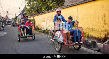 Moto rickshaws with their passengers driving in Kampung Taman neighborhood. Yogyakarta, Java, Indonesia. Stock Photo