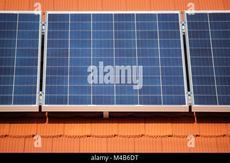 Solar panels on the red roof of a private house producing electricity, industrial background Stock Photo