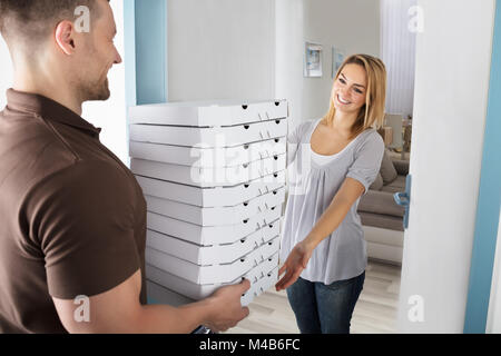 Pizza Delivery Man Giving Pizza Boxes To Smiling Young Woman Stock Photo