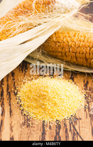 Corn groats and seeds, corncobs on wooden rustic table Stock Photo