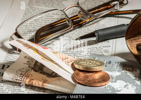 Glasses, coins, credit cards and banknotes on newspaper