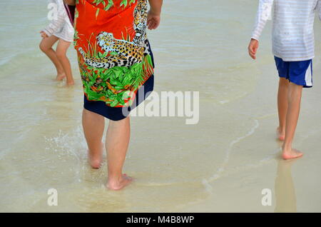 Family vacation by the sea. Grandma walking on the beach with her grandkids Stock Photo