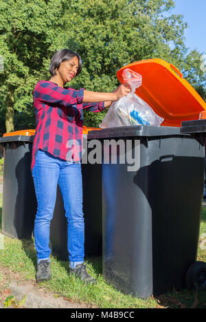 Standing dutch woman dropping plastic waste in trash bin Stock Photo