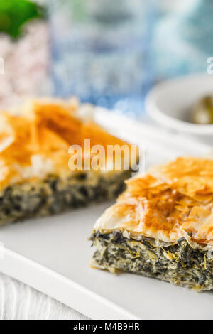 Greek pie spanakopita on the white plate with blurred accessorizes Stock Photo