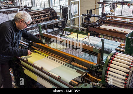 Fabric weaver operating mechanical flying shuttle loom / shuttle weaving machine in cotton mill / spinning-mill Stock Photo