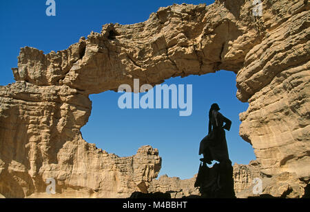 Algeria, Djanet. National Park Tassili n'Ajjer. Tassili Plateau. UNESCO World Heritage site. Sahara desert. Man of Tuareg tribe standing in arche. Stock Photo