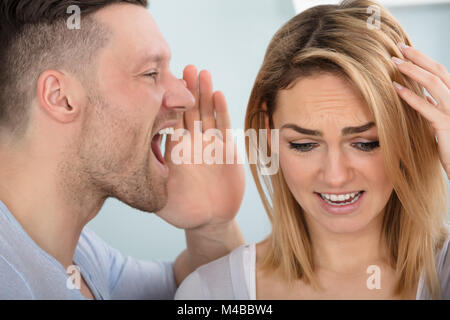 Close-up Of A Man Screaming In His Wife's Ear Stock Photo