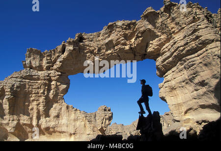 Algeria, Djanet. National Park Tassili n'Ajjer. Tassili Plateau. Sahara desert. Tourist. Woman hiking, standing in arch. UNESCO World Heritage site. Stock Photo