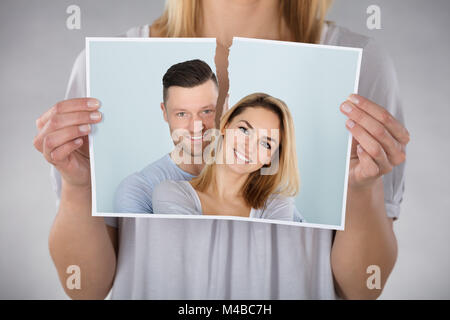 Close-up Of Woman Tearing Photo Of Smiling Couple Stock Photo