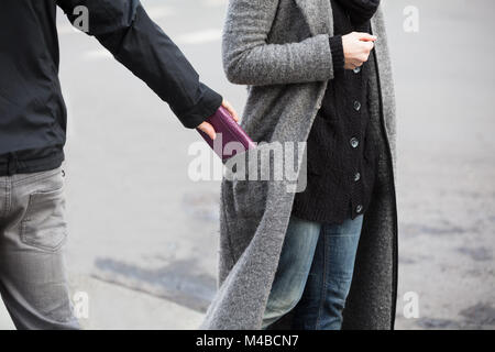 Close Of A Man Stealing Wallet From Woman's Coat Pocket Stock Photo