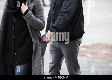 Close Of A Man Stealing Wallet From Woman's Coat Pocket Stock Photo