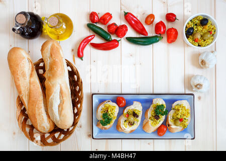 Bread rolls in basket with garlic and olive oil on light wood table Stock Photo