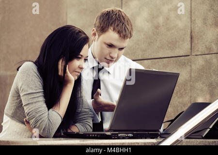 Young business couple using laptop outdoor Stock Photo