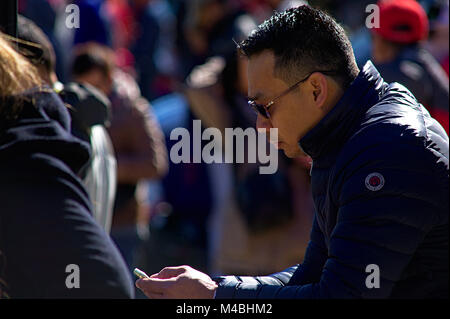 Man with fresh hair cut and sun glasses looking at his phone during Cherry Blossom Parade in Washington DC Stock Photo