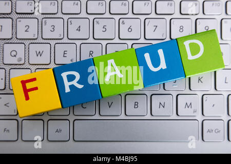 Fraud Word On Colorful Cubes Over Laptop Keyboard Stock Photo