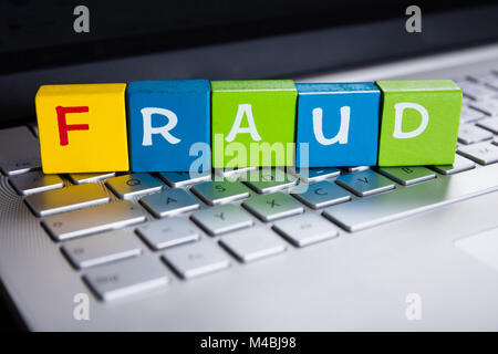 Fraud Word On Colorful Cubes Over Laptop Keyboard Stock Photo