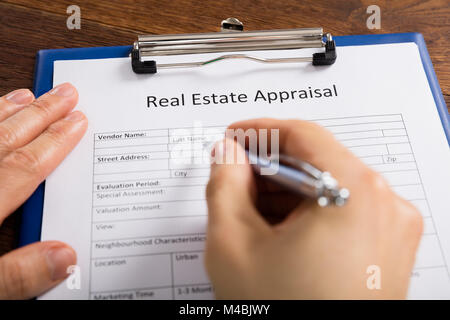 Close-up Of Person Hand Filling Real Estate Appraisal Form With Pen Stock Photo