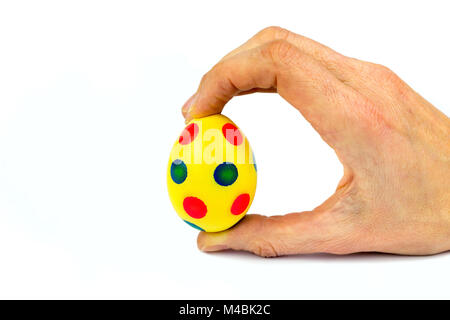 Hand holding painted yellow easter egg with dots Stock Photo
