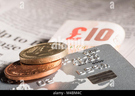 Coins, credit cards and banknotes on newspaper.