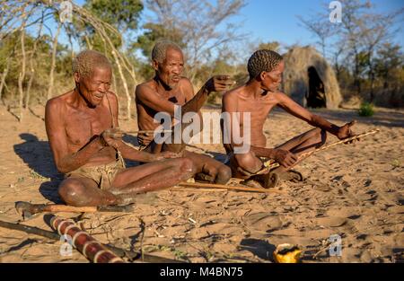 Bushmen of Ju/' Hoansi-San sitting on the ground,village //Xa/oba,near Tsumkwe,Otjozondjupa region,Namibia Stock Photo