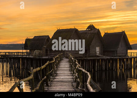 Wooden bridge and houses suspended over lake water Stock Photo