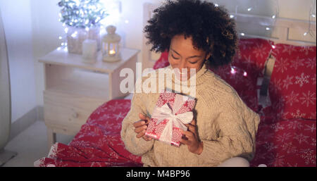 Smiling African woman holding Christmas gift Stock Photo