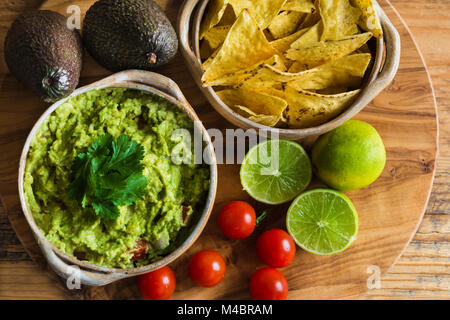 Guacamole dip with avocados limes tomatoes and tortilla chips Stock Photo