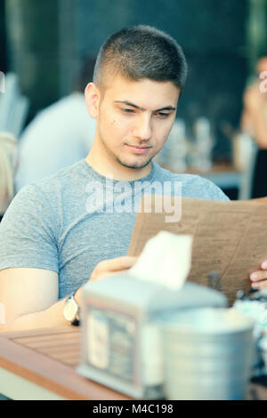 Man in outdoor restaurant looking at the menu Stock Photo