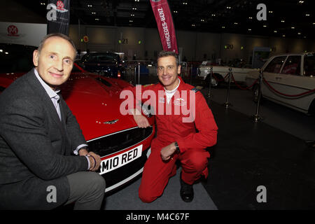 London, UK. 15th Feb, 2018. Lucky winner Humphrey Bradley poses with his Aston Martin Vanquish S Red Arrows car with Red Arrows pilot Squadron Leader Adam Collins ( in red flying suit ), Red 10 at the London Classic Car Show, Excel©Keith Larby/Alamy Live News Stock Photo