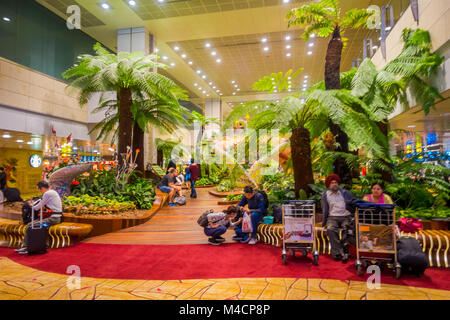 SINGAPORE, SINGAPORE - JANUARY 30, 2018: Indoor view of unidentified people sitting in a chairs in a small garden with plants inside of Singapore Changi Airport. Singapore Changi Airport is the primary civilian airport for Singapore Stock Photo