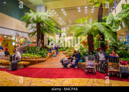 SINGAPORE, SINGAPORE - JANUARY 30, 2018: Indoor view of unidentified people sitting in a chairs in a small garden with plants inside of Singapore Changi Airport. Singapore Changi Airport is the primary civilian airport for Singapore Stock Photo