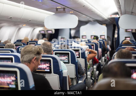 Interior of large commercial airplane with passengers on seats waiting to taik off. Stock Photo