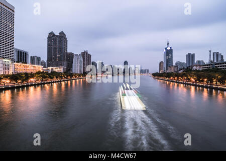 Tour boat, captured with blurred motion, sails on the Pearl river that crosses the Guangzhou downtown district in Guangdong province in China at twili Stock Photo