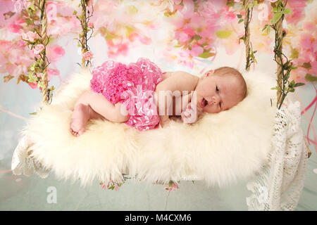 Newborn baby girl relaxing on nursery sensory swing, beautiful new baby relaxed and happy Stock Photo