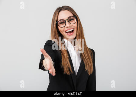 Portrait of a friendly businesswoman dressed in suit standing with outstretched hand for greeting isolated over gray background Stock Photo