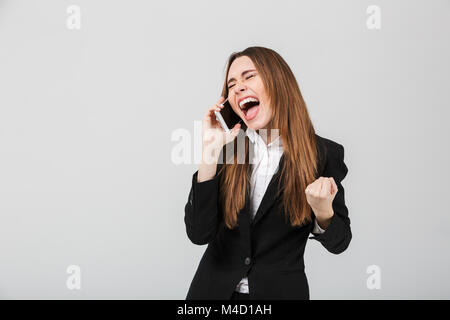 Happy pretty lady screaming and showing winner gesture while talking on smartphone isolated Stock Photo