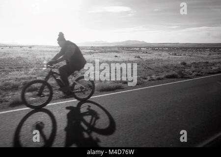A blurred bicycler on a bright desert road . Stock Photo