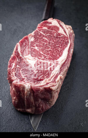 Raw Dry Aged Wagyu Entrecote Steak on a Japanese Knife Stock Photo