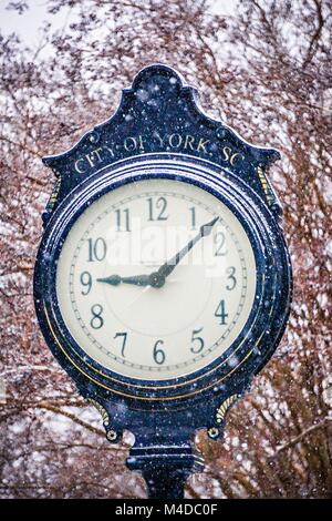 vintage historic street clock with snow falling in winter Stock Photo