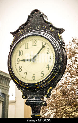 vintage historic street clock with snow falling in winter Stock Photo