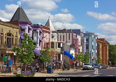 WASHINGTON DC, USA – MAY 9, 2015: Row houses and businesses in Adams Morgan neighborhood on a perfect spring day with young people walking on the stre Stock Photo