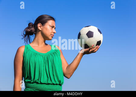 Young woman holding football on hand with blue sky Stock Photo