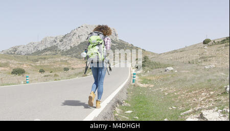 Back view of woman walking down road Stock Photo